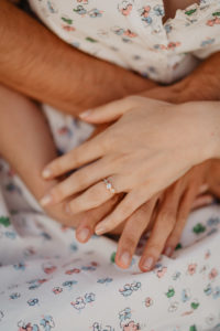 Photographie des mains d'un couple avec leurs bagues de fiançailles.