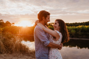 Photographie d'un couple enlacés devant un lac.