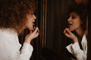 Photographie d'une femme se mettant du rouge à lèvres.