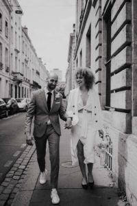 Photographie d'un couple en tenue de mariage marchant dans la rue.