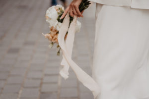 Photographie d'une femme tenant un bouquet de fleur dans sa main.